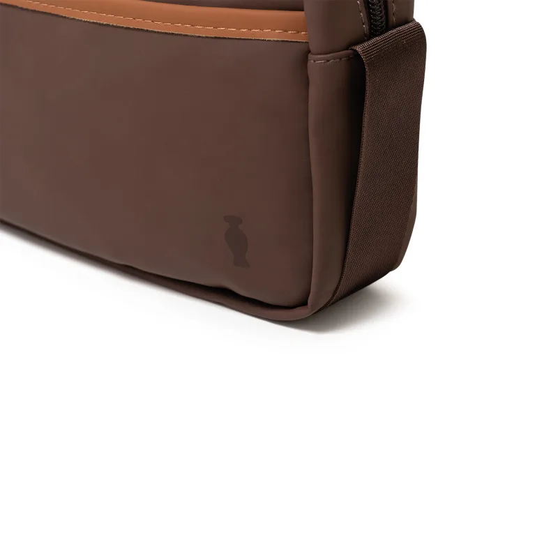 Bolsa tipo nécessaire retangular na cor marrom escuro e detalhes marrom claro com alça de transporte e zíper.