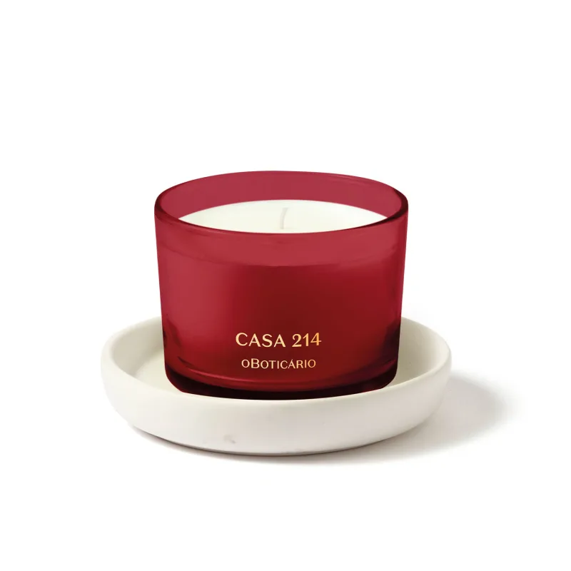 Vela perfumada branca em recipiente vermelho acompanhada de um suporte para velas branco, ambos da marca Casa 214.
