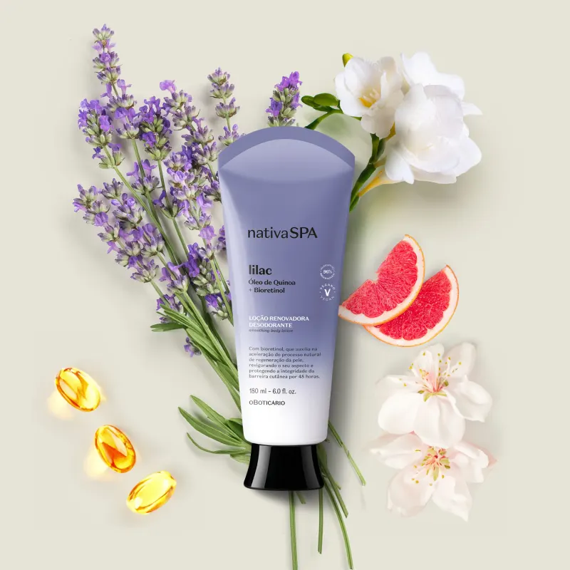 Bisnaga em degradê de lilás e branco com tampa preta e letras brancas e pretas de loção renovadora hidratante corporal Nativa SPA Lilac cercado por flores de lavanda, rosas brancas e fatias de toranja vermelha sobre fundo bege claro.
