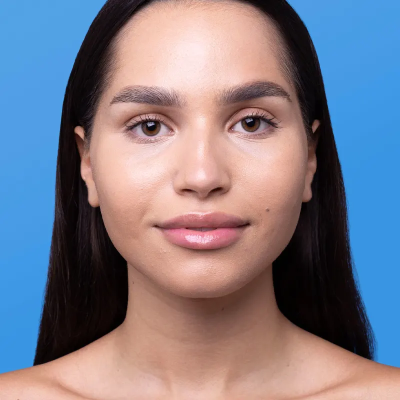 Retrato de uma mulher com cabelos escuros em um fundo azul, sugerindo que ela esteja usando o protetor solar Boti.Sun cor 3.0.