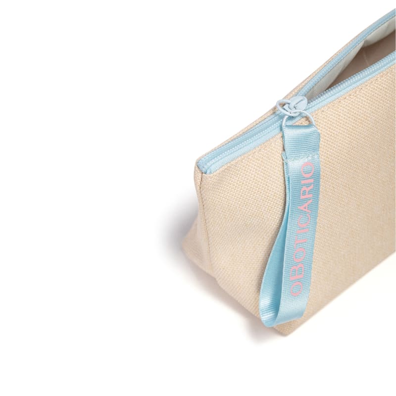 Necessaire de tecido bege com zíper e alça azul, com a marca O Boticário bordado em letras bege.