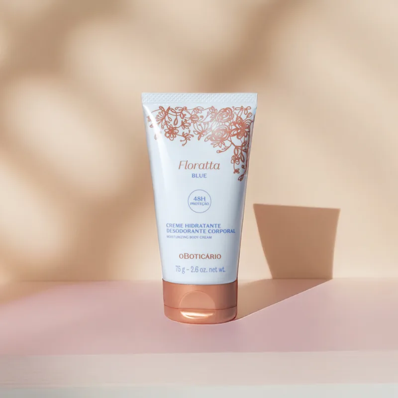 Bisnaga azul claro, letras azuis, detalhe floral e tampa na cor dourada contendo creme hidratante corporal Floratta Blue em fundo bege com sombras.