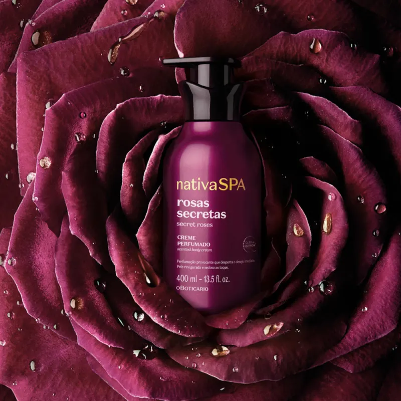 Imagem do creme corporal Nativa SPA, um creme perfumado de rosas secretas, em um ambiente com pétalas de rosa roxas e gotas de orvalho, sugerindo um contexto de relaxamento e cuidado pessoal.