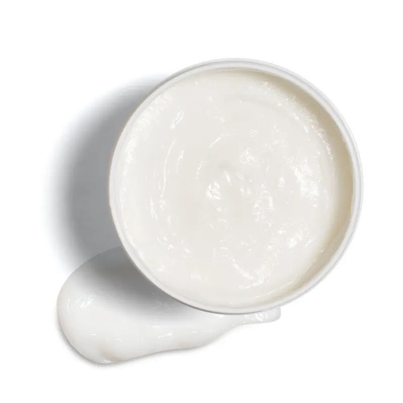 Imagem de um pote branco aberto contendo creme branco dentro e um pouco do mesmo produto no fundo da imagem.