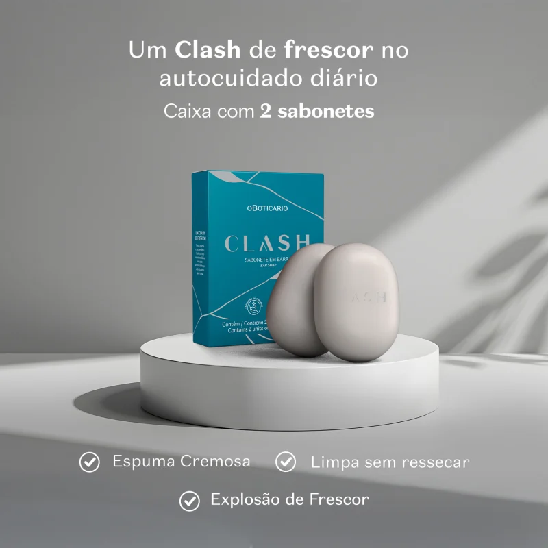 Caixa de sabonete em barra da marca Clash sobre superfície branca, com dois sabonetes brancos ao lado. Ambiente monocromático em tons de cinza. Texto informa que o produto oferece espuma cremosa, limpa sem ressecar e proporciona explosão de frescor.