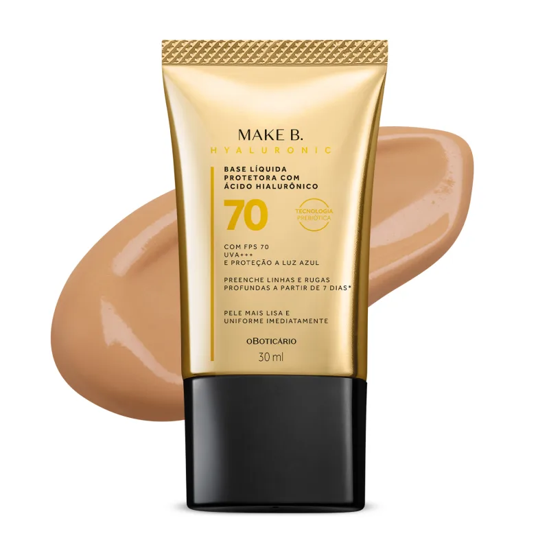 Imagem do tubo de base líquida protetora Make B. Hyaluronic Cor 4. Ele é dourado, possui tampa preta e informações em letras pretas e laranja. Atrás da embalagem está a textura do produto, mostrando sua intensidade e a real cor da base.
