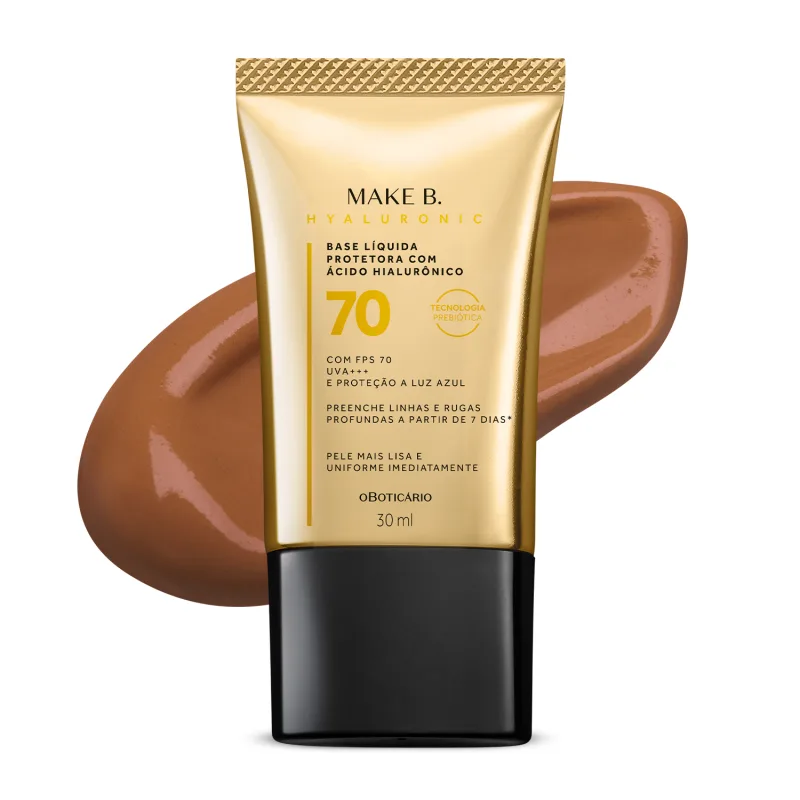 Imagem do tubo de base líquida protetora Make B. Hyaluronic Cor 70. Ele é dourado, possui tampa preta e informações em letras pretas e laranja. Atrás da embalagem está a textura do produto, mostrando sua intensidade e a real cor da base.