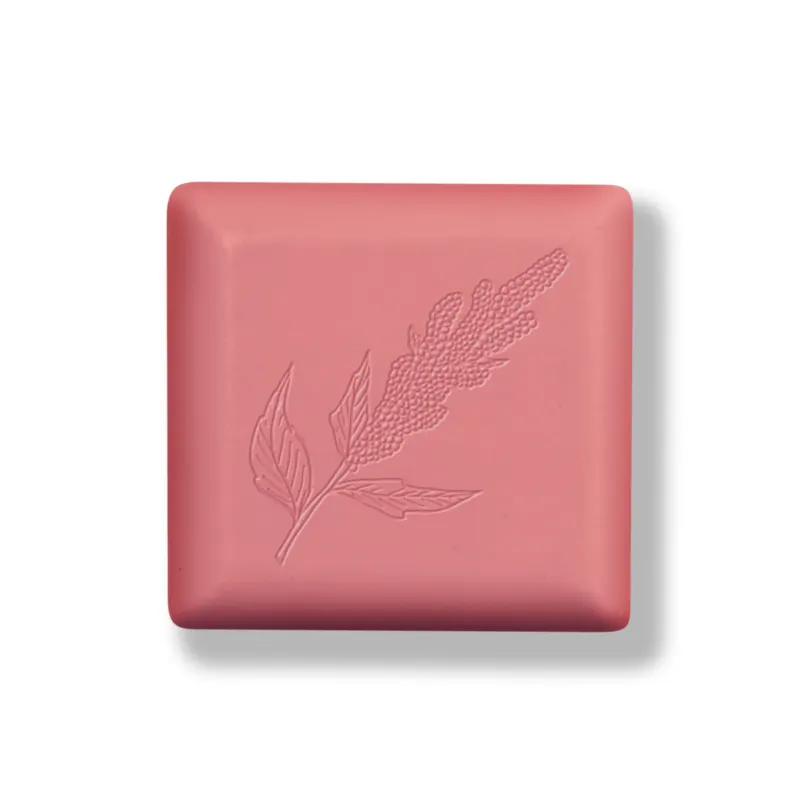 Barra de sabonete quadrada de cor rosa com baixo relevo em formato de folha em tom ligeiramente mais escuro que a barra.