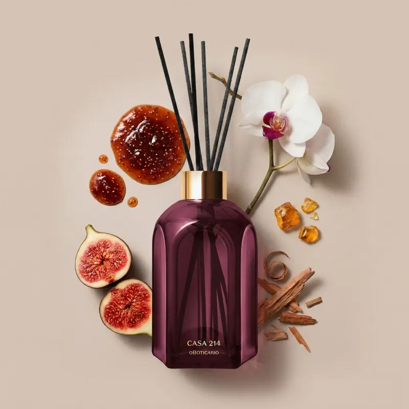 Vidro roxo do difusor de ambientes Casa 214 Figo Magnífico com varetas pretas em meio a flores de orquídea branca, fatias de figo e cristais âmbar, sobre superfície bege.