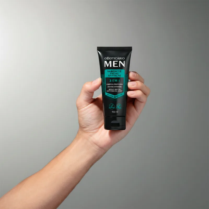 Imagem da embalagem do sabonete líquido facial Men com embalagem preta e verde, apresentado em uma mão contra um fundo neutro, sugerindo um ambiente minimalista e focado no produto.