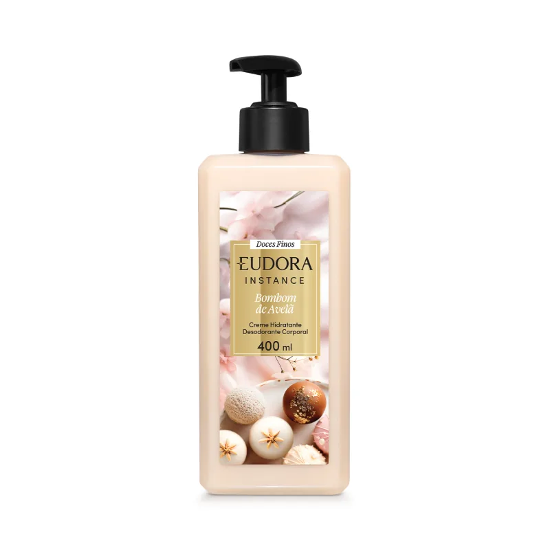 Embalagem plástica transparente com imagem de bombom de açúcar na cor bege, nozes, especiarias e flores decorativas no rótulo. Retângulo dourado com o nome Eudora Instance Bombom de Avelã 400ml em letras pretas e brancas. Bomba dosadora preta como tampa.