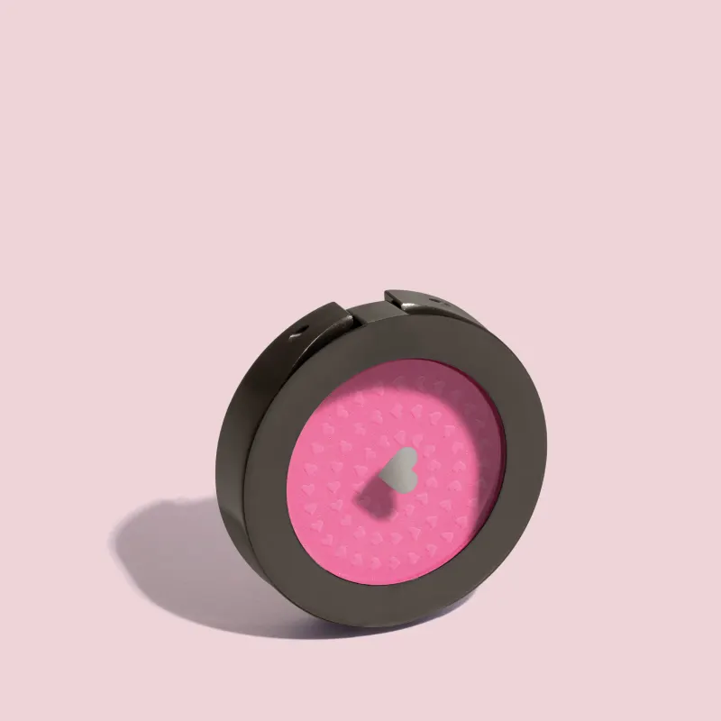 Estojo compacto redondo na cor preta com tampa transparente com coração ilustrado contendo 2g de blush em pó compacto Rubor Rosa Rosandilex da marca Quem Disse, Berenice? em fundo lilás.