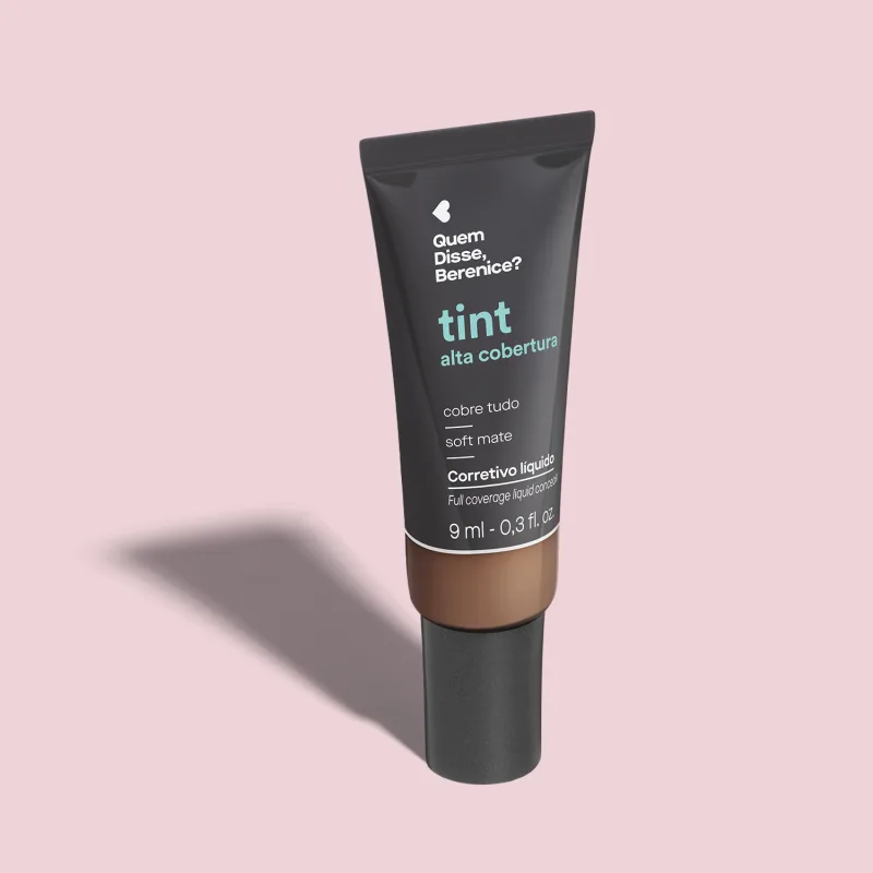 Corretivo líquido Tint Alta Cobertura Cor 315 Quem Disse, Berenice? em embalagem de 9ml na cor preta com parte do frasco transparente mostrando a tonalidade do produto, tampa preta e letras azuis e brancas. O fundo é lilás com sombra.
