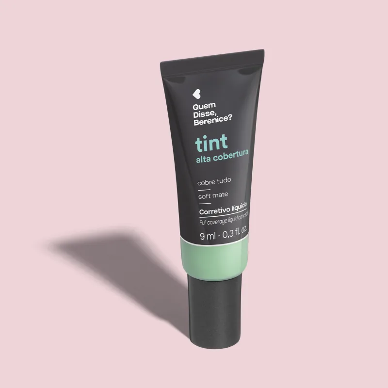 Trata-se de um corretivo líquido de alta cobertura da marca Tint. O produto vem em um tubo plástico preto com parte inferior transparente mostrando a cor verde. O texto em português "Quem Disse, Berenice?" e "cobre tudo" está impresso.