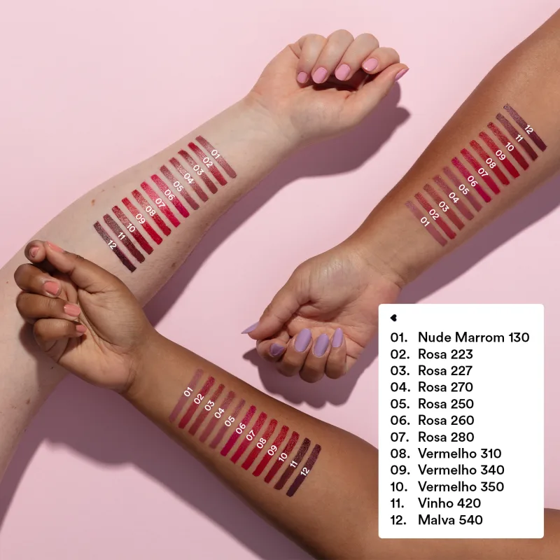 Imagem mostra três braços de cores diferentes estendidos sobre superfície rosada, sendo um de pele negra, um de pele branca e um de pele parda, todos com diversos tons de batons aplicados sobre eles e seus códigos.