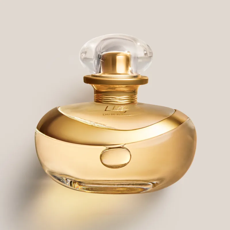 A imagem mostra um frasco de perfume da marca Lily. O frasco tem uma forma orgânica e elegante, com um anel dourado no centro do corpo.