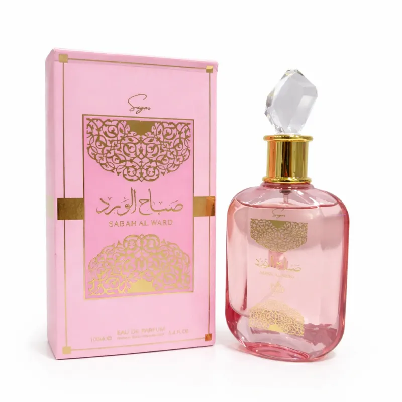 Frasco de perfume rosa com detalhes dourados, embalado em caixa rosa com padrões florais dourados. O rótulo exibe o nome "Sabah Al Ward" em árabe e em inglês.