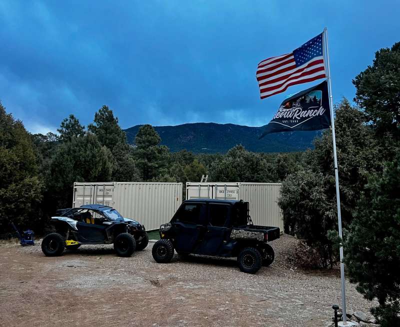 Customer photo: a custom flag and a USA flag on a flagpole beside two side-by-sides