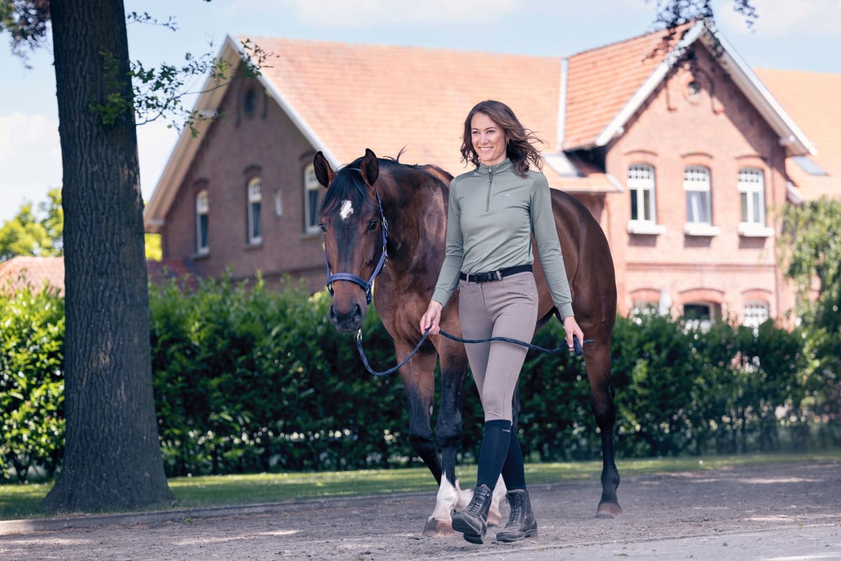 Lady with horse in front of house.