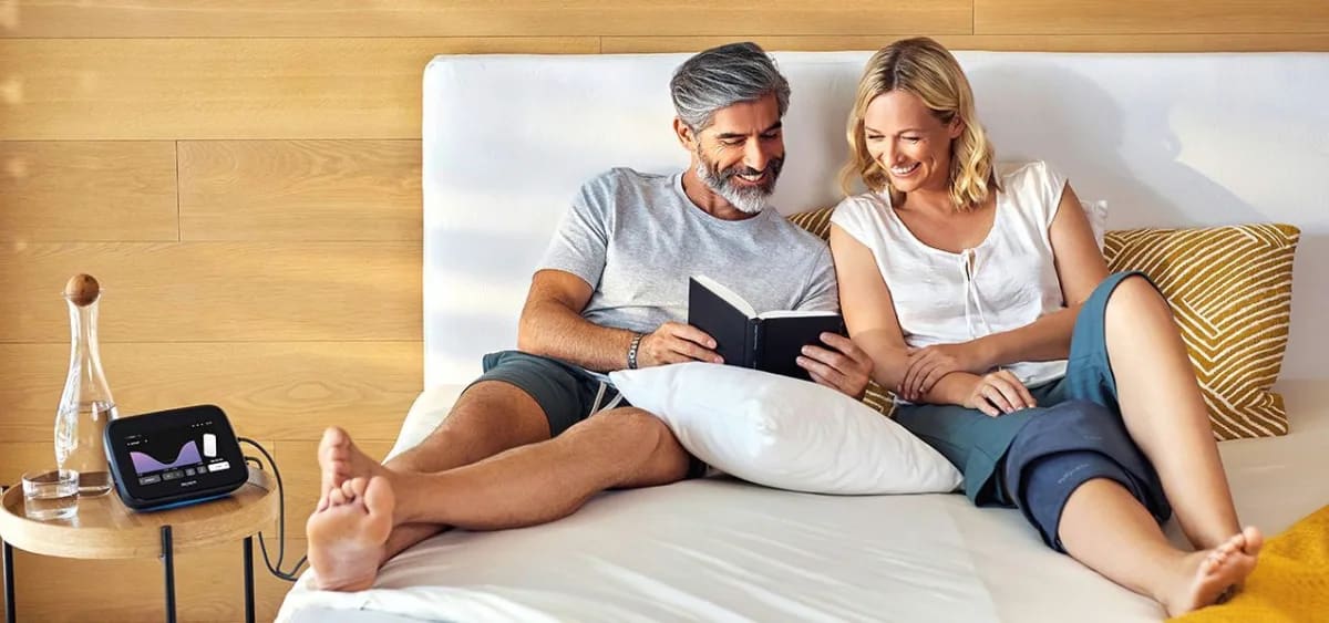 Couple reading on a bed while using the B.Bed Evo