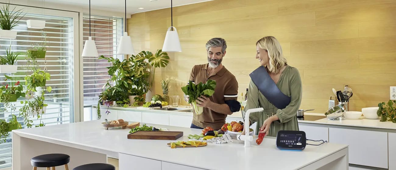 A couple preparing vegetables in their kitchen while using BEMER