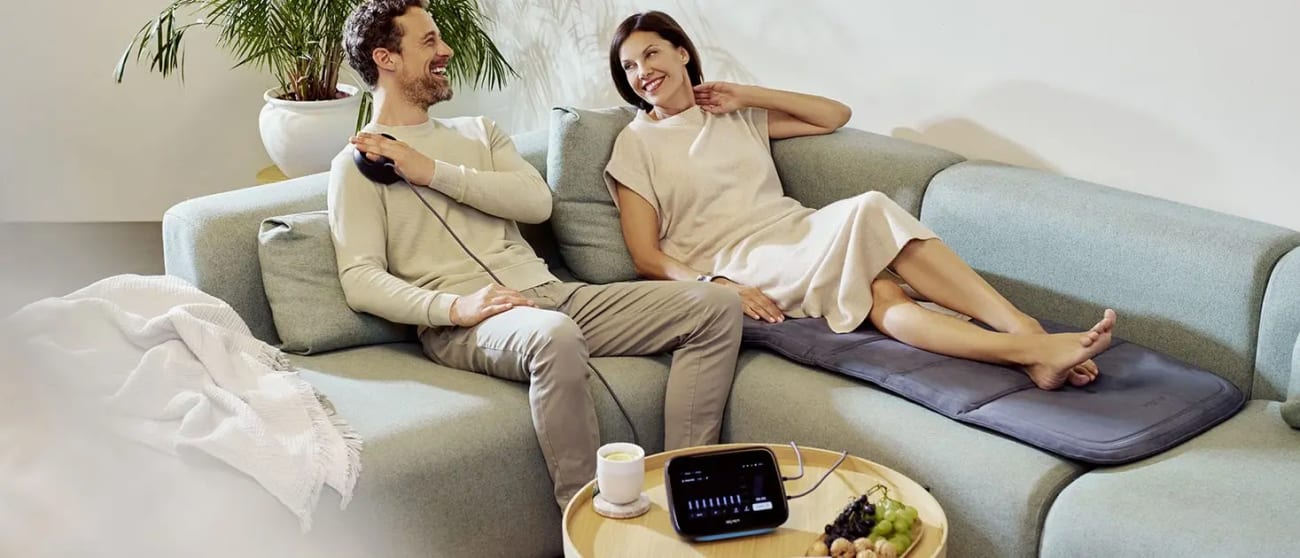 Couple relaxing on a couch while using BEMER