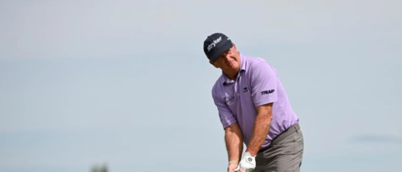 A golfer stands on a golf course preparing to swing his golf club