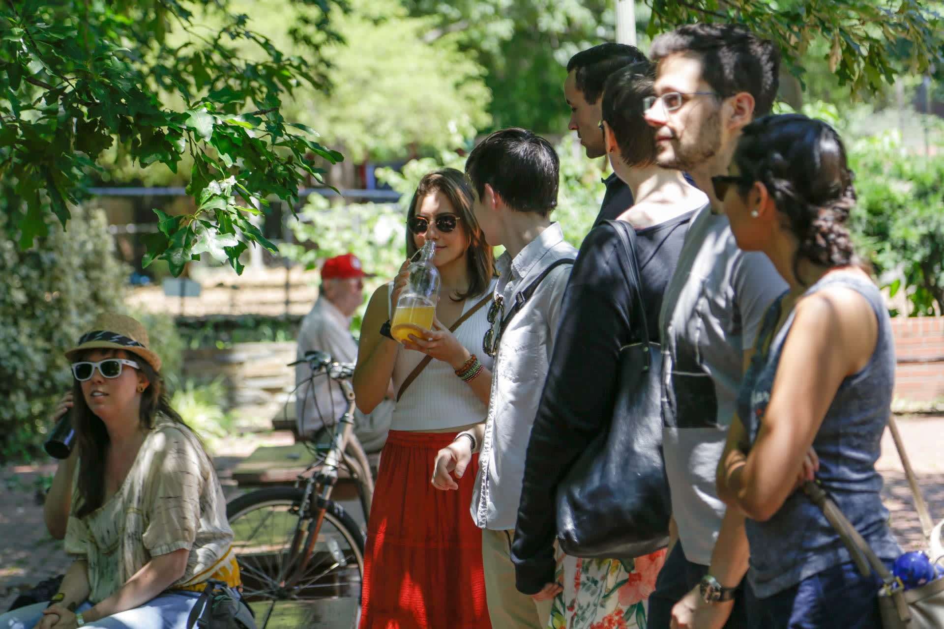 A group of people standing in a park smelling bottles of liquid