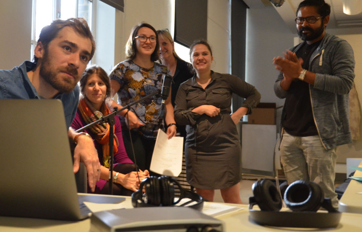 A group of people smiling while looking at a screen