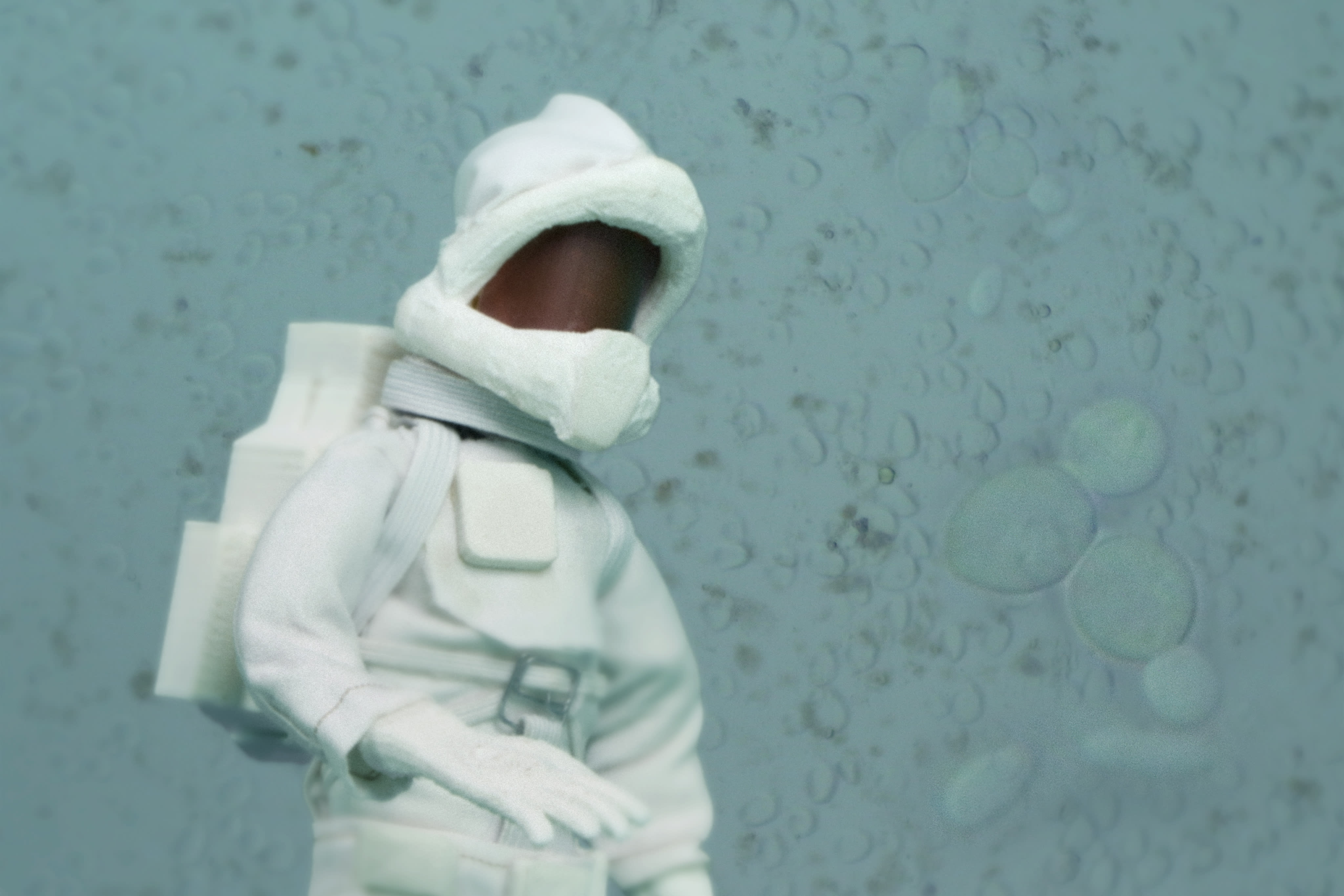 An astronaut standing in front of blue microbes
