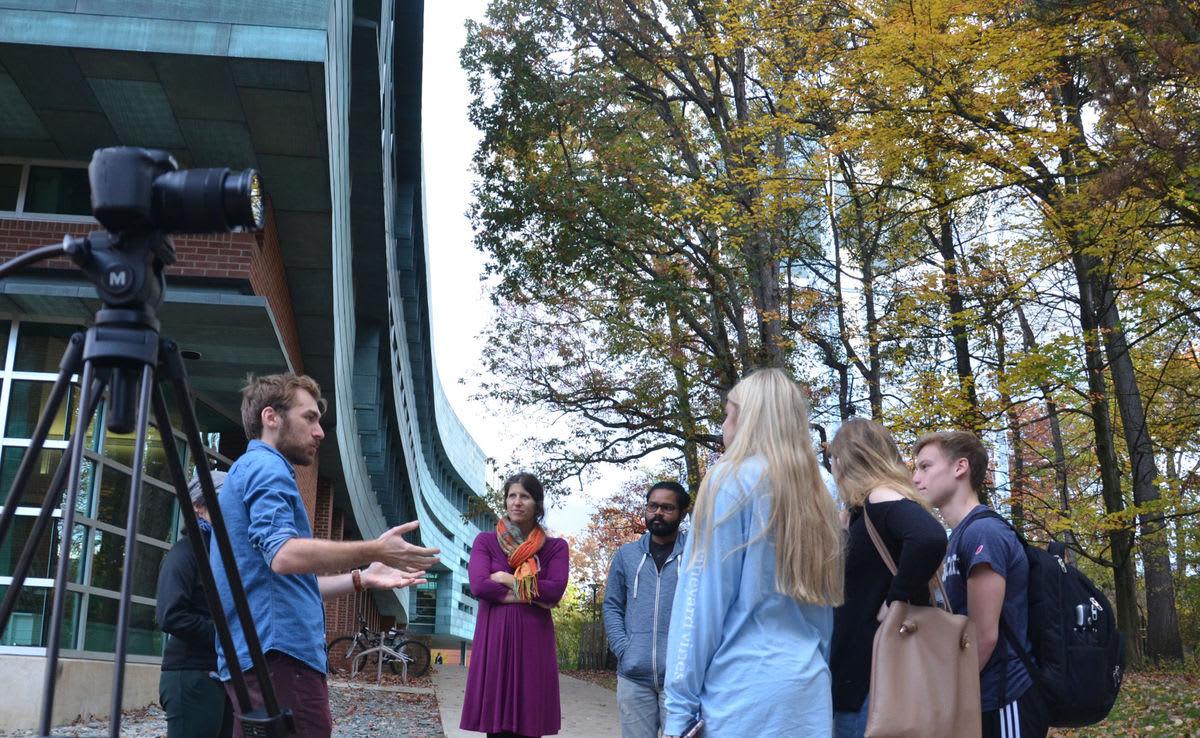 Group of people talking outside with a camera on tripod