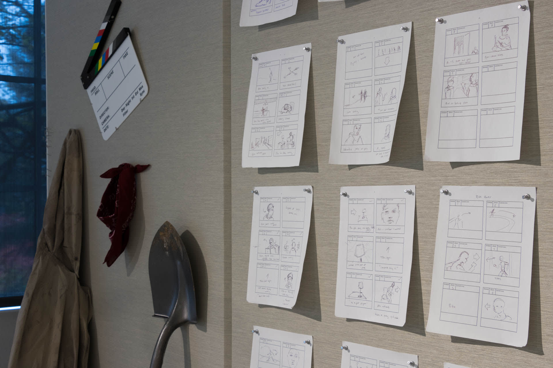 Storyboard papers tacked to a wall with a shovel and assorted props