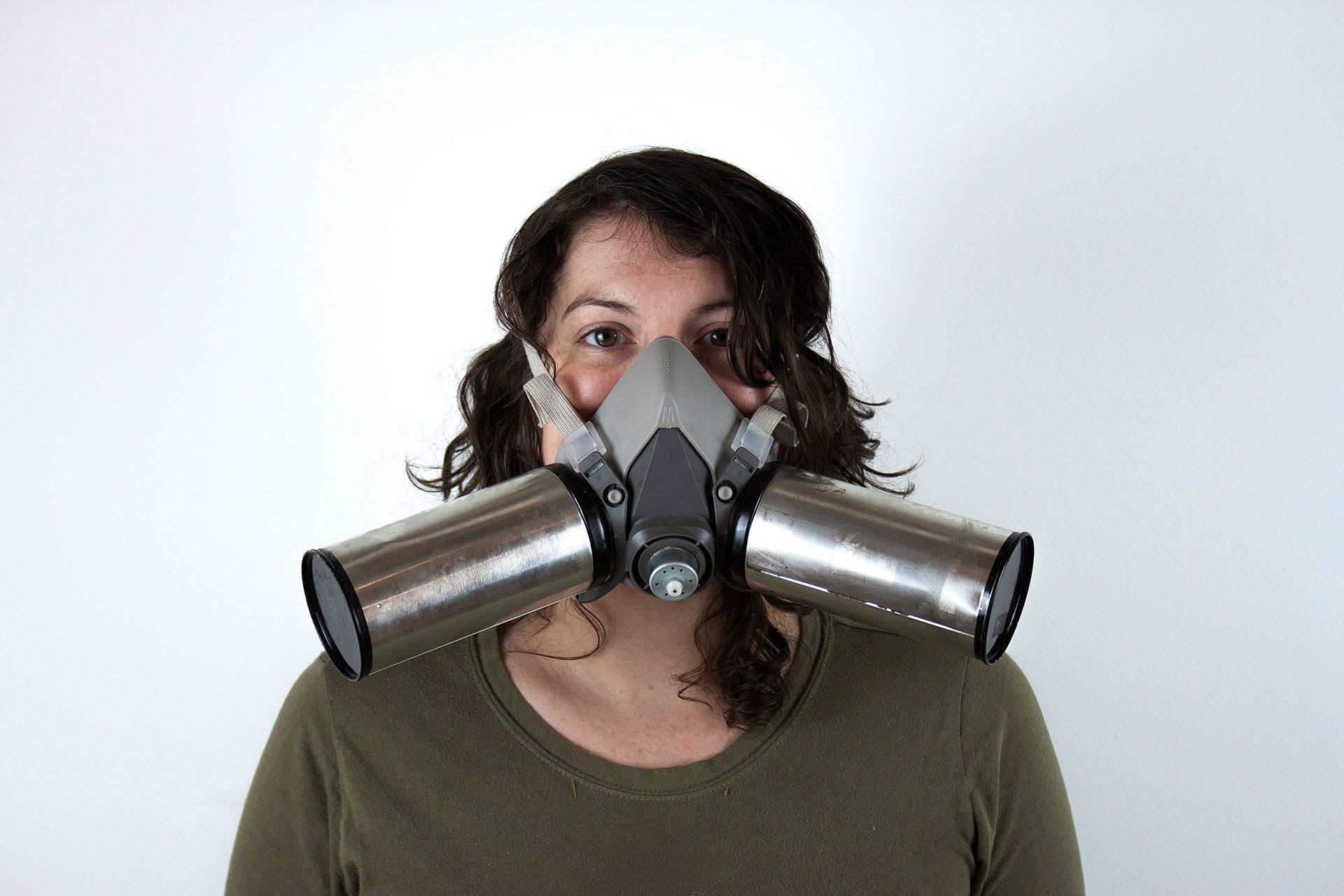 A woman facing the camera with a large metal mask incorporating two round canisters