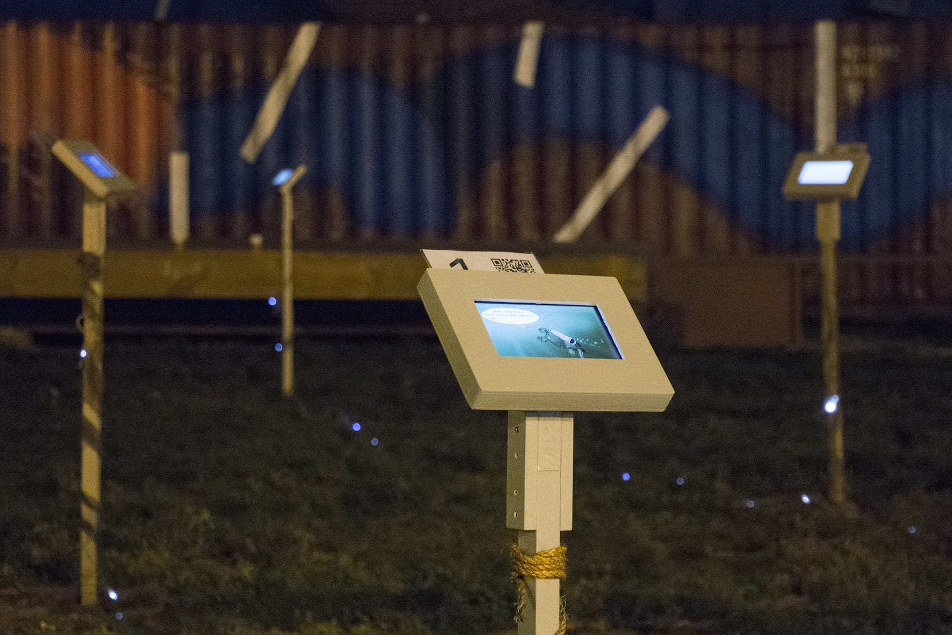 Several screens on vertical posts in a park at night