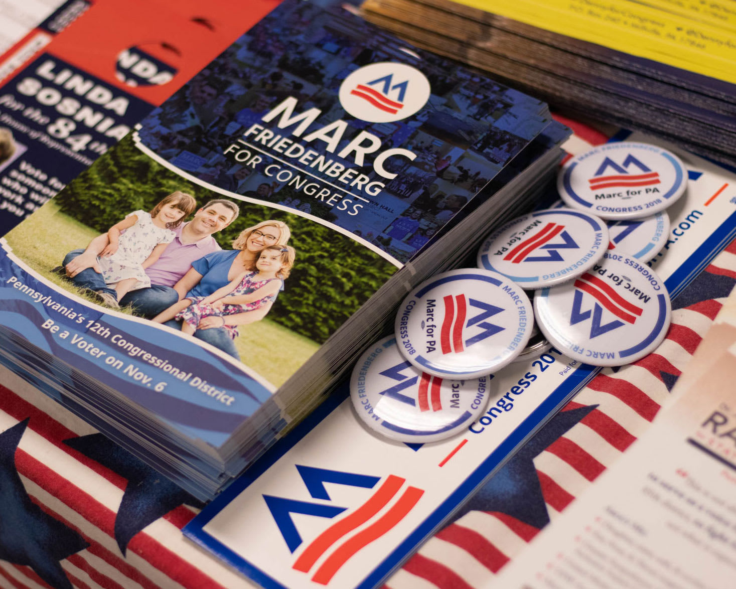 A table full of political flyers and buttons with an M logo