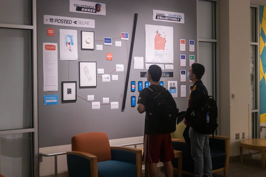 A wall of papers and framed objects in a gallery