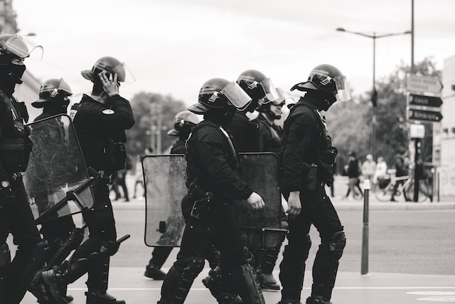 Black and white photo of police marching in a row, urban setting