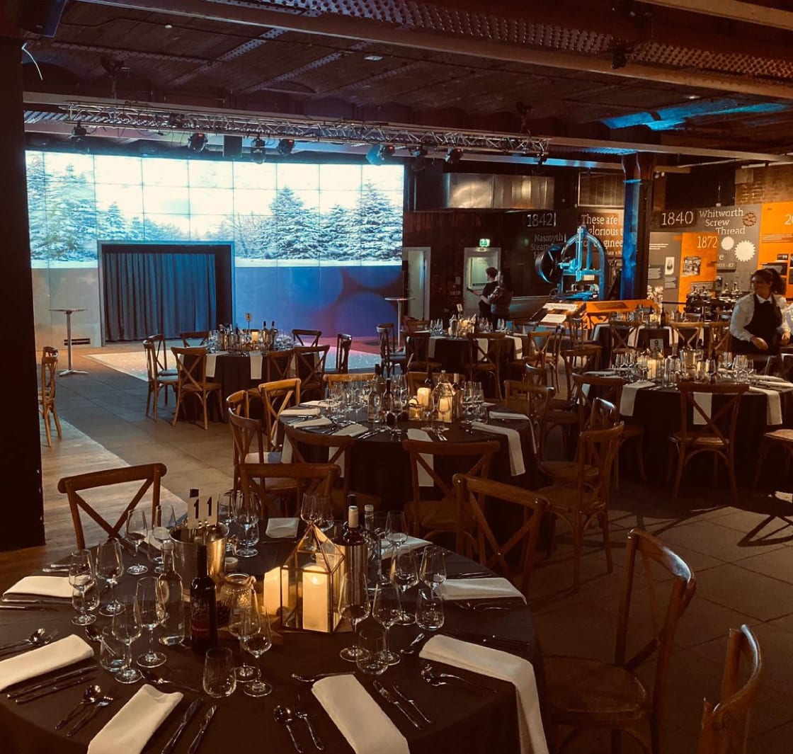 A room set up with tables laid ready for an event in the museum