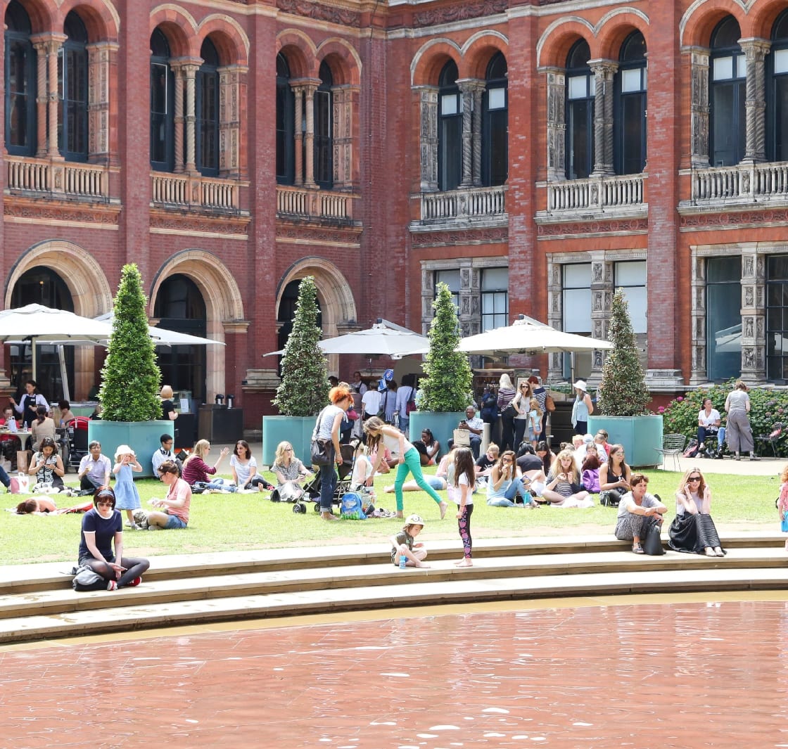 People sitting on the grass outside of the V&A Museum