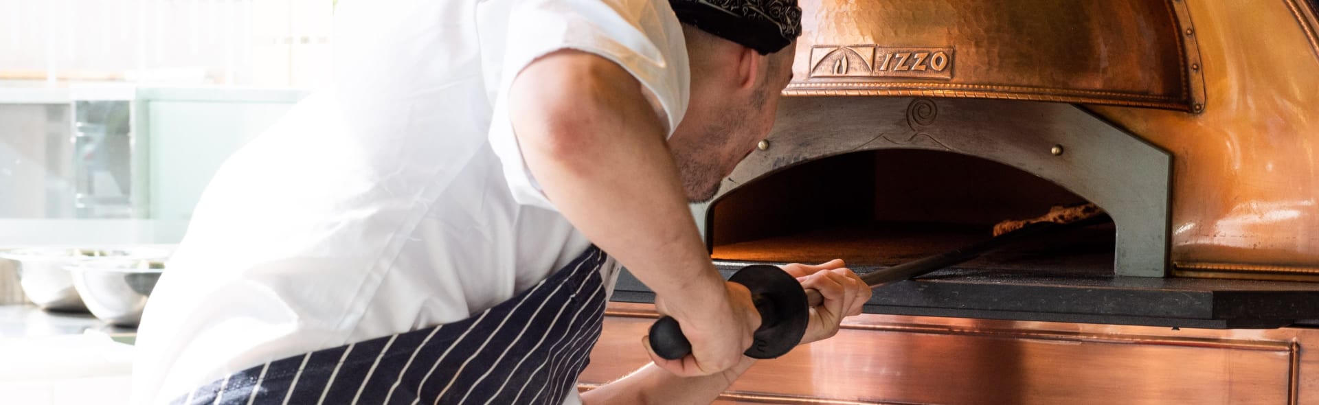 Chef placing pizza in pizza oven