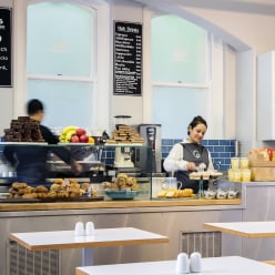 A photo of people restocking the cake stand preparing hot drinks
