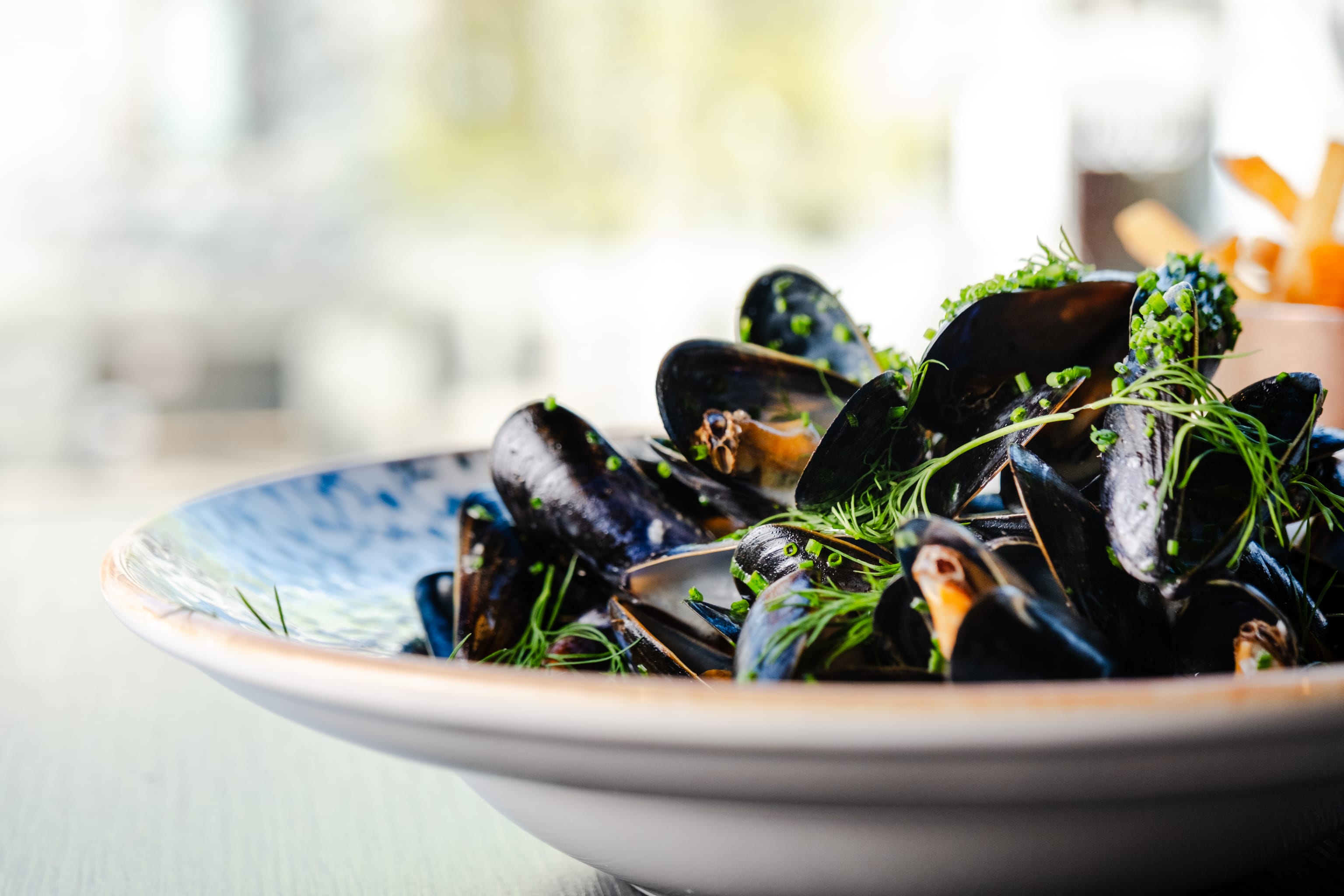 Blåskjell i en bolle med friske urter på toppe