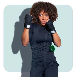 A young woman wears the Antelope EMS suit with leggings. She is holding a boxing pose. A young woman wears the Antelope EMS suit with leggings. She is holding a boxing pose.