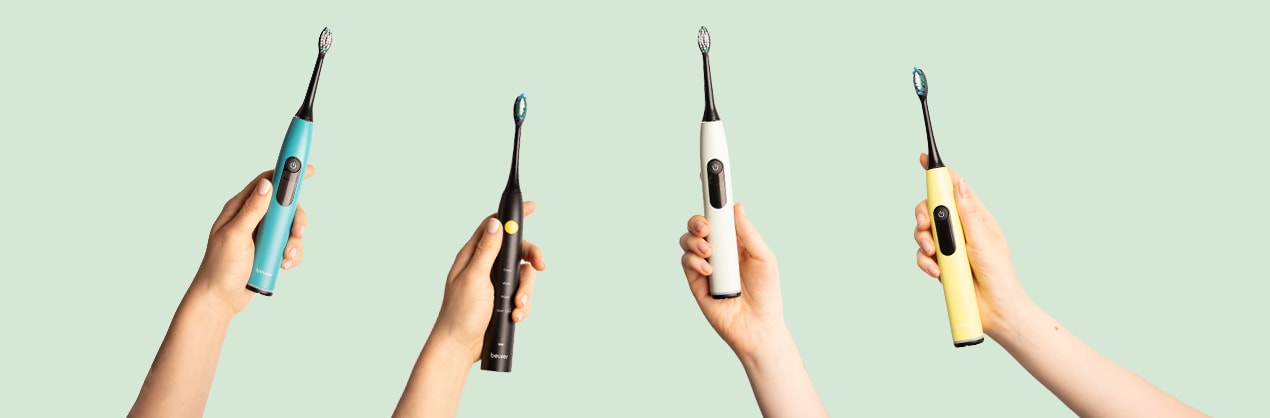 Four hands holding up the four Beurer SC 50 electric sonic toothbrushes in different colors.