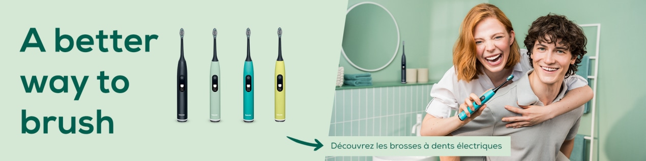 Bannière de la page d'accueil consacrée aux soins dentaires « Une meilleure façon de se brosser les dents » présentant les brosses à dents soniques Beurer SC 50 en quatre couleurs, à côté d'un couple souriant dans la salle de bain. Elle tient la SC 50 en couleur Ocean Breeze.