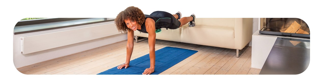 Eine junge Frau trainiert zuhause. Sie führt einen Liegestütz aus, ihre Füße sind auf einer Couch. Sie trägt das Antelope EMS Tank Top zusammen mit der EMS Shorts.
