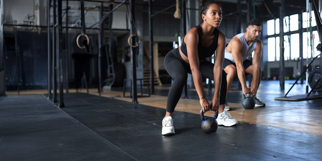 Una joven y un joven hacen deporte juntos en el gimnasio.