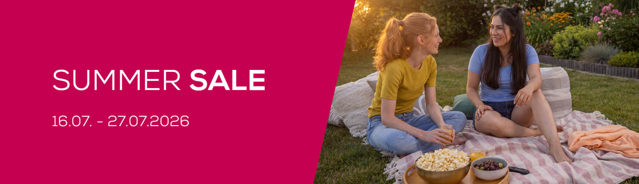Zwei junge Frauen freuen sich über den Summer Sale und sitzen im Garten