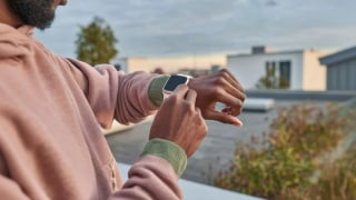 A man is standing outside, using his Apple Watch