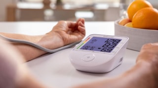 A person is measuring their blood pressure using a Beurer upper-arm blood pressure monitor